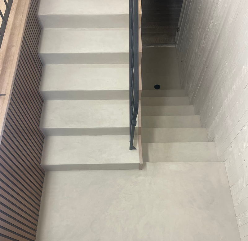 Modern staircase with white steps and a metal railing in a well-lit hallway.